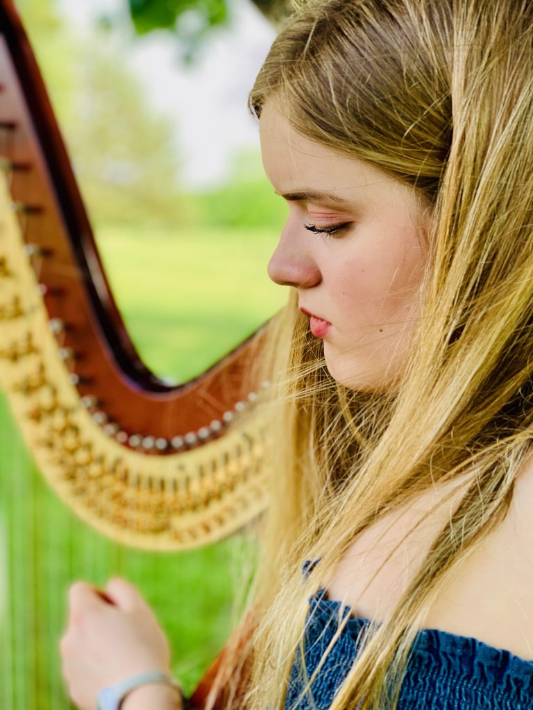 A photo of Stella playing the harp.